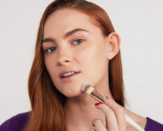 chica aplicando base de maquillaje en rostro