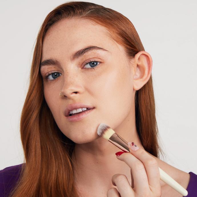 chica aplicando base de maquillaje en rostro