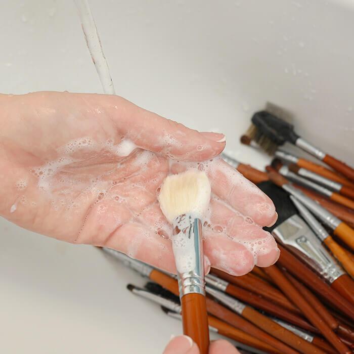 how to clean makeup brushes thumbnail Close-up image of woman's hand cleaning brushes in the sink Mobile