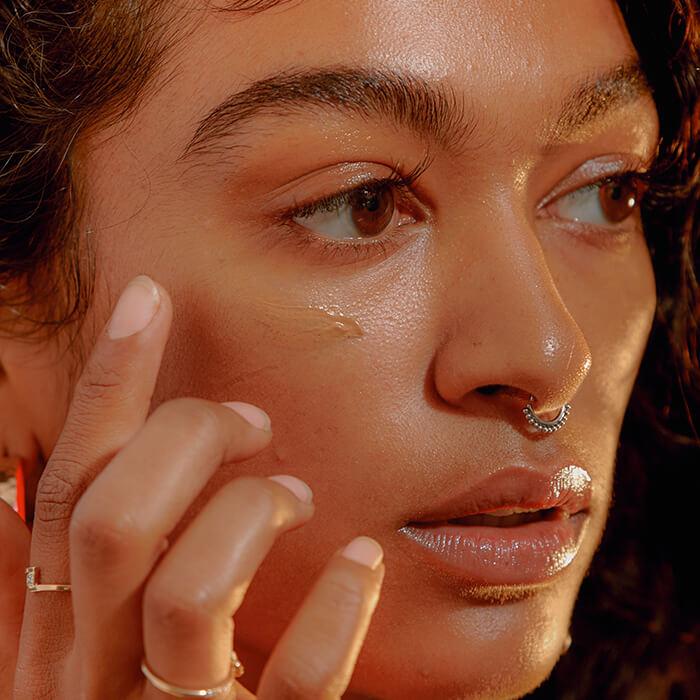 Portrait of a young woman applying liquid foundation Mobile